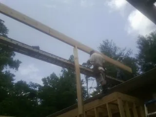 Carpenter setting a ridge beam over a new addition frame — Ice Dam Removal by Roofing Brothers in Salina